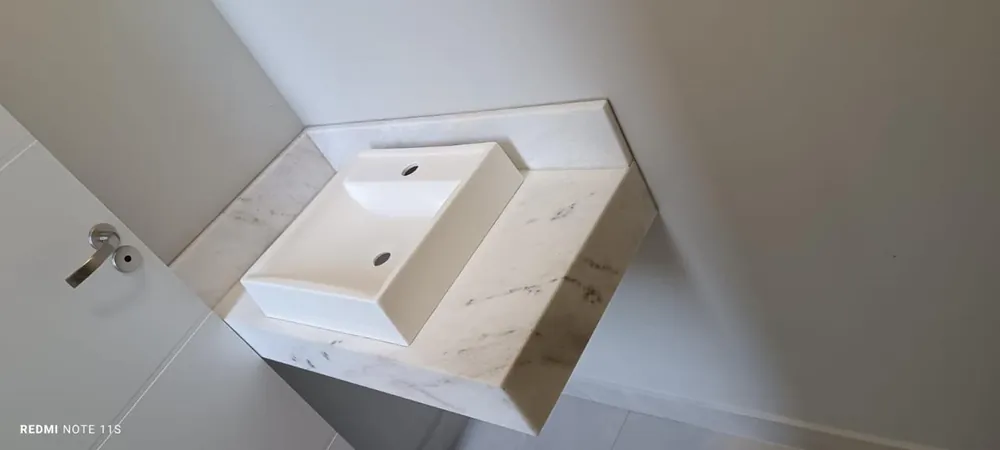Bancada de banheiro em mármore branco com cuba esculpida na própria pedra