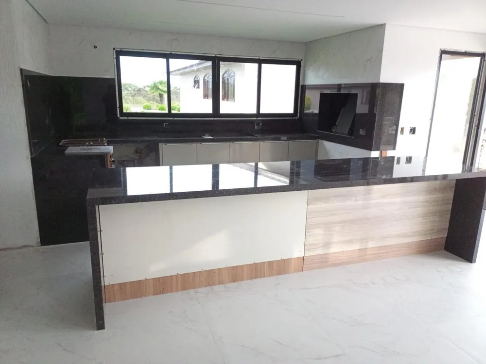 Ilha de cozinha em granito preto polido com frontão em pedra e marcenaria clara