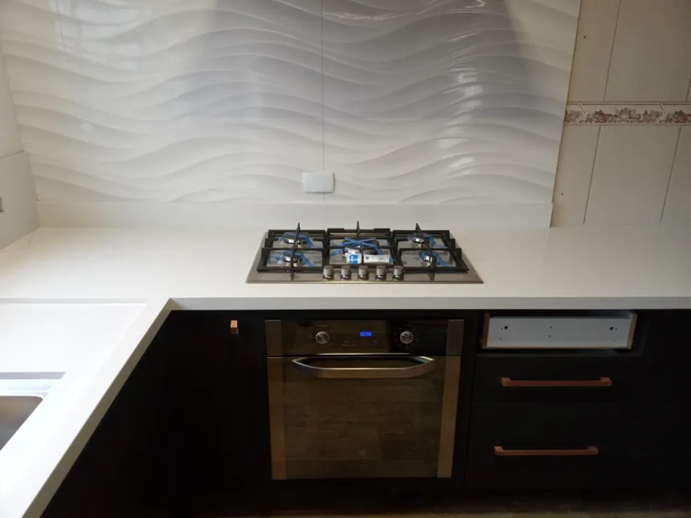 Bancada em quartzo branco em formato de L com recorte para cooktop