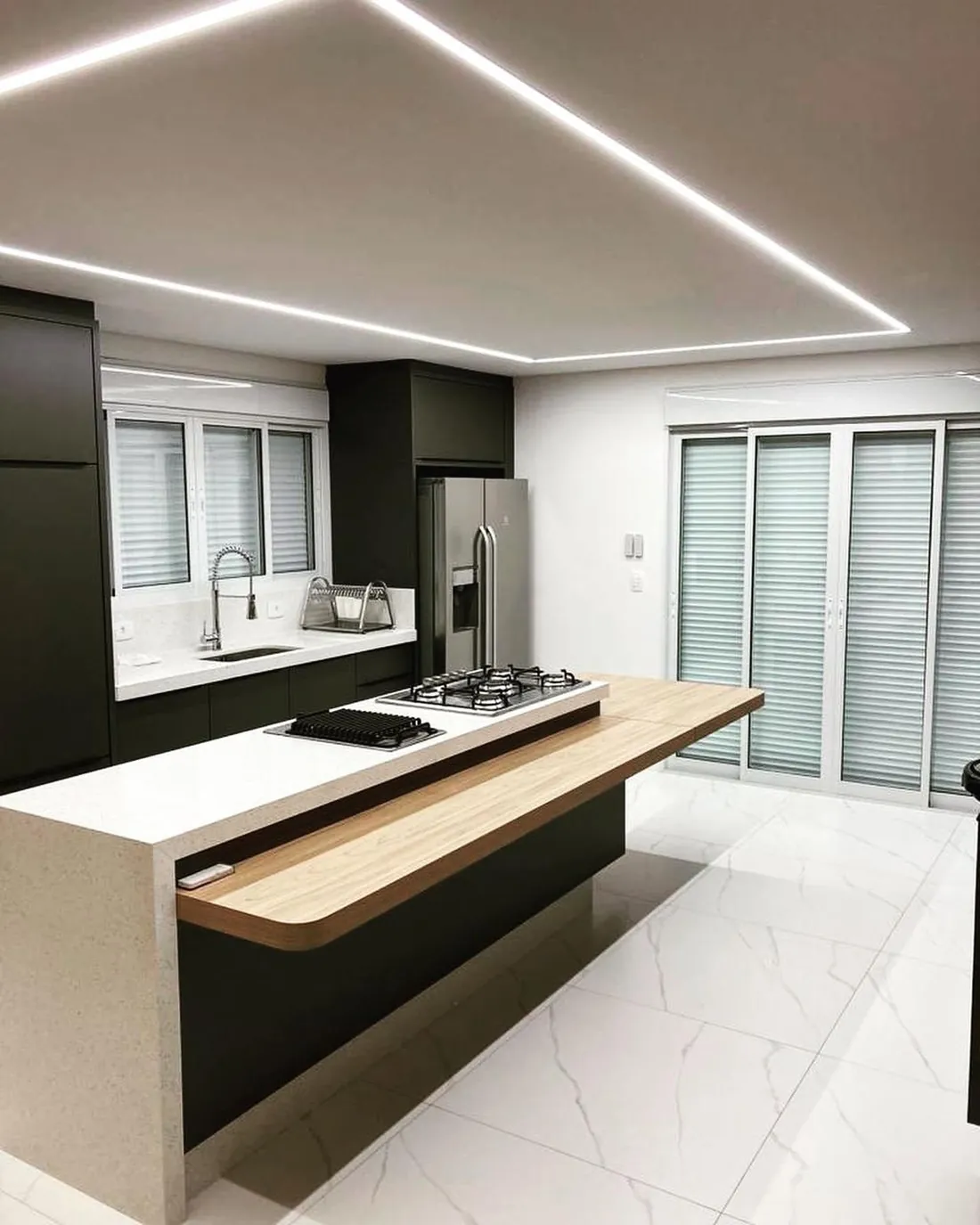 Sala e cozinha integradas com ilha central em pedra clara