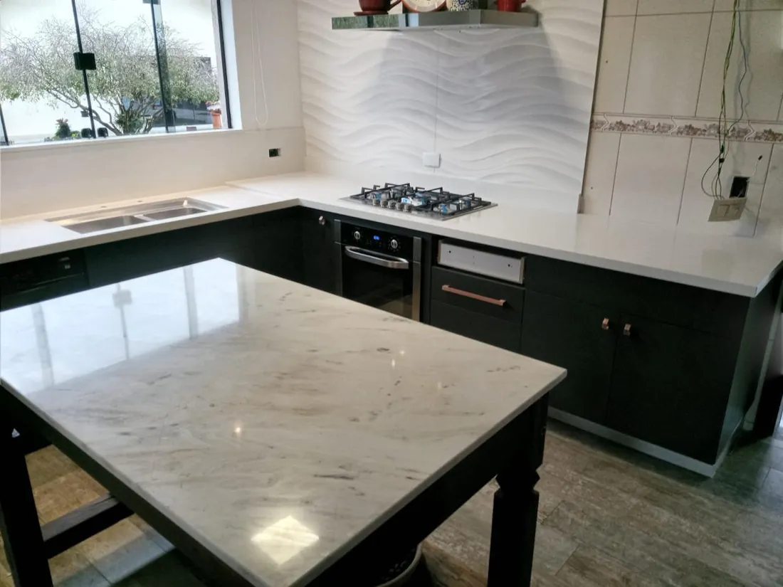 Cozinha com bancada em mármore claro e marcenaria escura