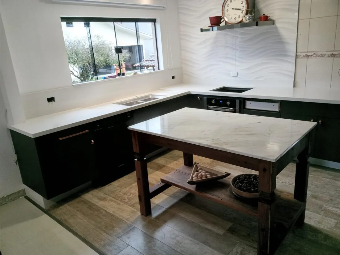 Bancada em pedra clara com frontão contínuo e vista para janela